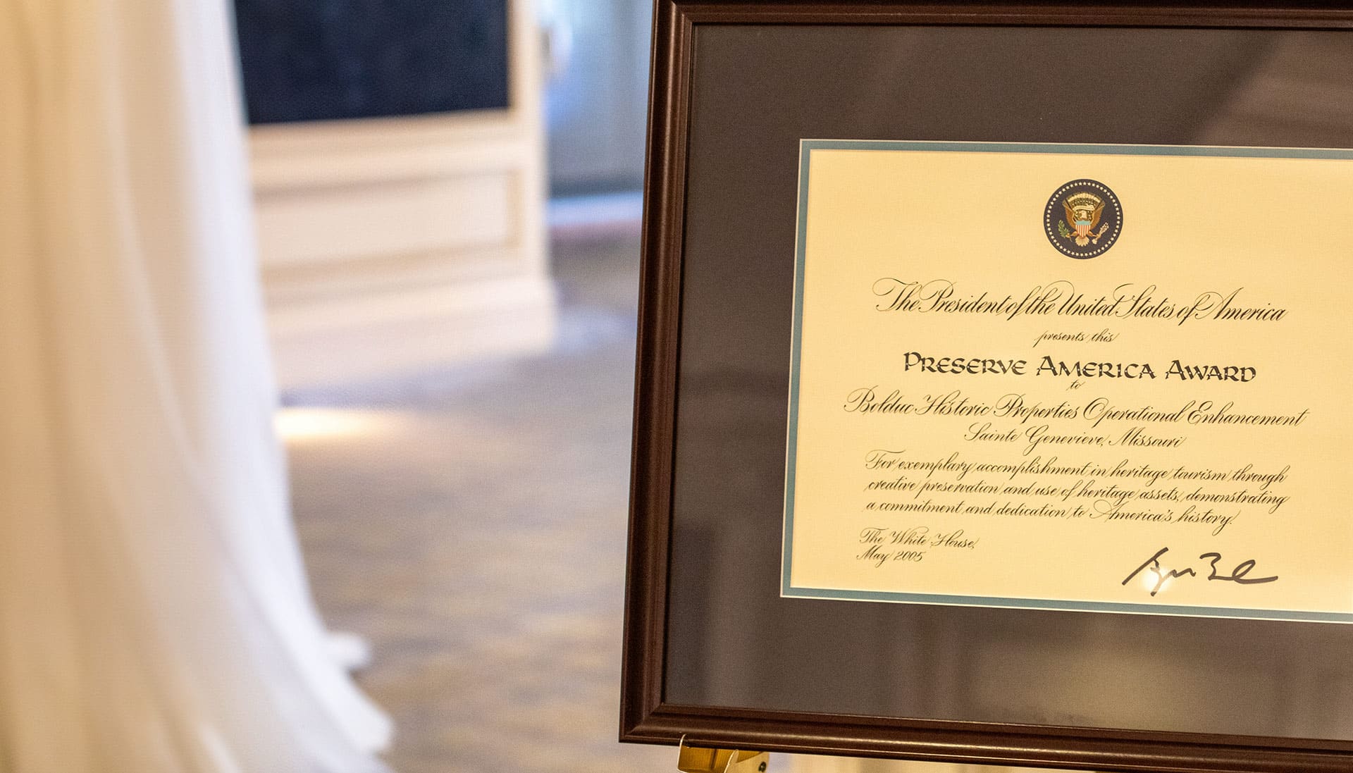 Close up of the Preserve America Award certificate in a brown wooden frame on an easel