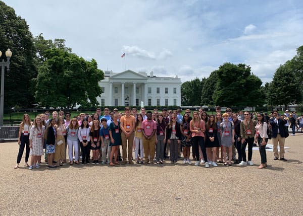 Group of teenagers stand for a photo in front of the White House