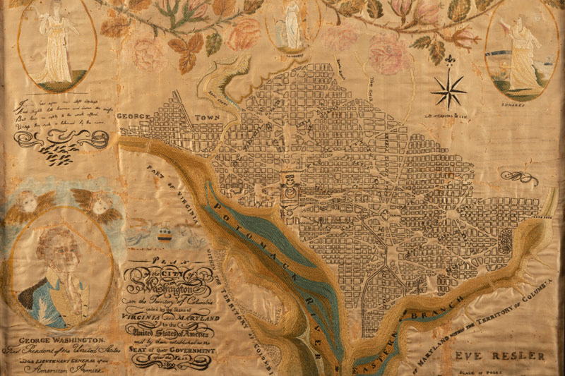 close up of embroidered cloth depicting the Washington, DC area and surrounded by historical portraits