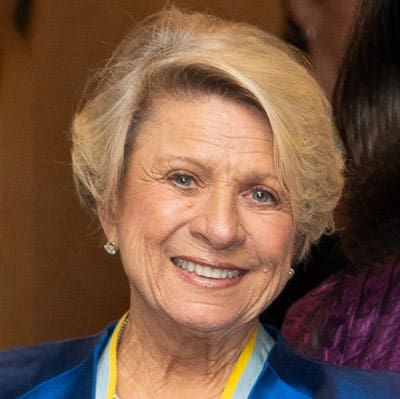 Headshot of Stuart Cobb, a blonde woman wearing diamond earrings