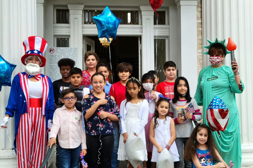 Women dressed as Uncle Sam and the Statue of Liberty pose for the camera with a group of children