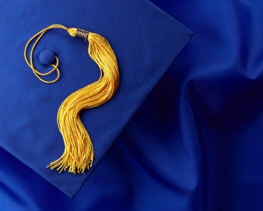 Close up of blue graduation robes and cap with a golden tassel