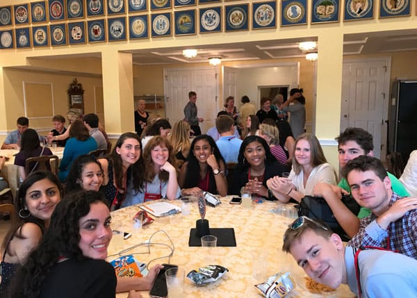 Group of teenagers sit around a round table and smile at the camera